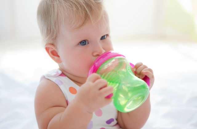 Bebê tomando água no copo de transição